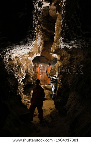 Five men, strong physique, explore the cave. Men dressed in special clothes to pass through the cave and stopped, looking at the map.