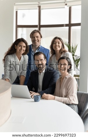 Five millennial and mature businesspeople smiling look at camera pose together in modern office. Executive managers, successful company members, corporate staff portrait. Career, promotion, business