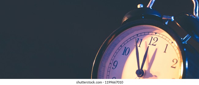 Five minutes to midnight. Changing the clocks, time adjustment, daylight savings or new year concept on retro analog clock, wide copy space background for internet banner - Shutterstock ID 1199667010