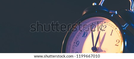Five minutes to midnight. Changing the clocks, time adjustment, daylight savings or new year concept on retro analog clock, wide copy space background for internet banner