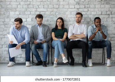 Five Multi Racial Young People Applicants Sitting In Line On Chairs In Office Corridor Feels Nervous Unsure Job Interview Success, Highly Competitive Job Market, Tension Rises Due To Waiting Concept