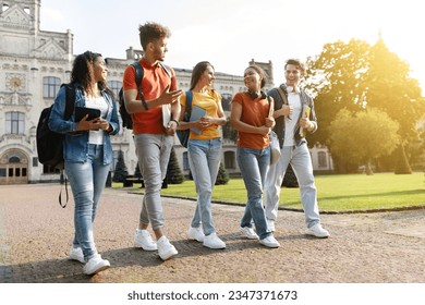 Five multiethnic students chatting and laughing while walking together at university campus, group of happy young people with books and backpacks going to classes or having fun after lessons - Shutterstock ID 2347371673