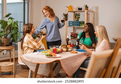 Five multigenerational female friends are enjoying their christmas dinner party at home, toasting with red wine and having fun together - Powered by Shutterstock