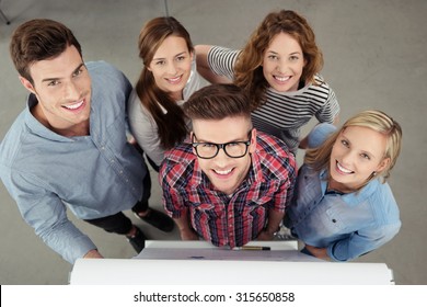 Five Optimistic Office Workers Smiling at the Camera From the Top View Inside the Office.