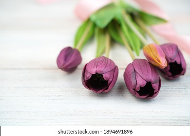 Five Purple Tulips Lie On A Light Wooden Table. Side View, Close-up. Concept Of Festive Backgrounds, March 8, Spring.