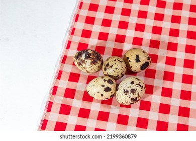 Five Quail Eggs On A Red And White Napkin Background