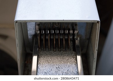Five quarters inserted into the payment mechanism of a worn, white metal coin-operated machine, depicting a financial transaction in a public utility or vending setting, symbolizing everyday economics and vintage technology.