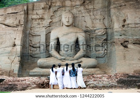 Five religious women are standing and admiring the great Samadhi Statue in Polonnaruwa, Sri Lanka.