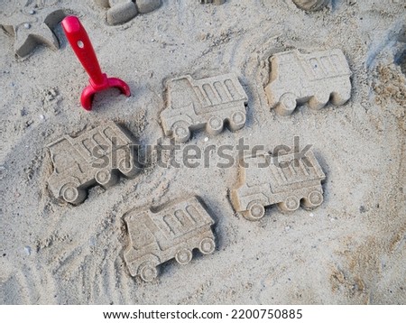 Five sand truck figurines in the playground with red shovel