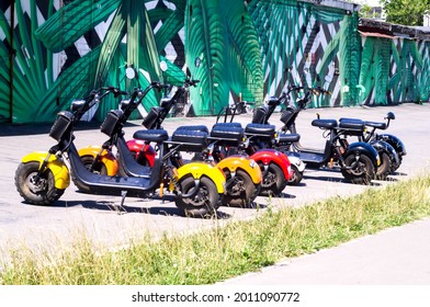 Five scooters are standing side by side on the street