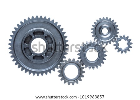 Five steel cog wheels from an engine are connected together over a plain white background.
