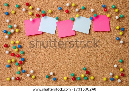 Five sticky notes in various colors with a lot of pushpins and blank space on cork background. Empty colorful notes on cork board for a greeting (congratulations) message. 