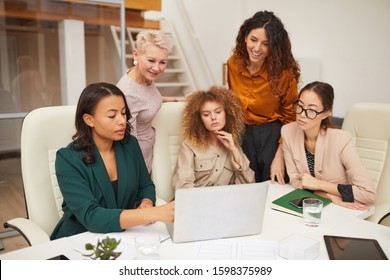 Five Successful Ethnically Diverse Women Of Different Age Watching Something On Laptop In Office Horizontal Shot