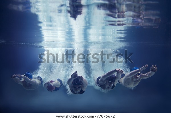 Five swimmers jumping together into water\
isolated blue background