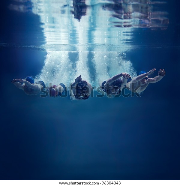 Five swimmers jumping together into water\
isolated blue background