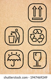 Five Symbol On Cardboard Box - This Way Up, Do Not Litter, Recycling, Keep Dry And Fragile. Close-up.