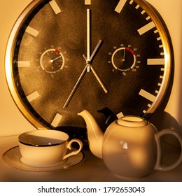 Five O’clock Tea With A Big Wall Clock Showing Five O’clock Sharp, A Teapot And A Cup On A Small Dish.