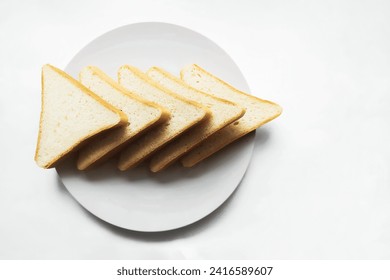 Five triangular slices of bread on a white round plate on a light background closeup. Pointer right top view