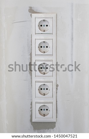 Five white Power sockets with frame on white wall as a background. Minimalism concept