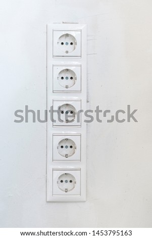 Five white Power sockets with frame on white wall as a background. Minimalism concept