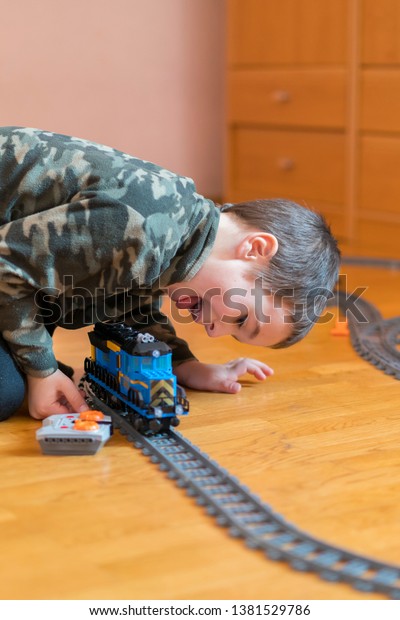 Five year old\
boy playing on the floor by rail. Little boy playing with railway\
lying on the floor. vertical\
photo