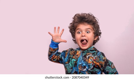 Five Year Old Boy Shows Five Fingers. Little Happy Kid Waving Hi. Portrait Of Surprised Amazed Child With Open Mouth. Advertising Childrens Products. Wow. Shocked And Happy News.