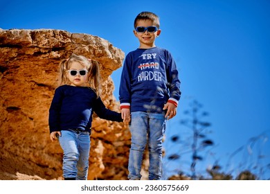 FIVE YEAR OLD BOY AND THREE YEAR OLD GIRL IN A LANDSCAPE NEAR THE SEA
