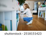 Five year old girl selecting a book in municipal library