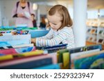 Five year old girl selecting a book in municipal library.