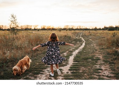 Five years girl wearing dress walking in the fields . Child enjoying summertime outside