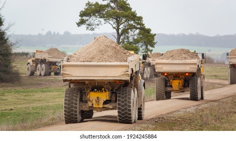 Five Yellow Volvo A40E And A40F Articulated Dump Truck Earth Movers Each Fully Laden With 25 Tonne Payload Convoy Across Salisbury Plain, Wiltshire UK