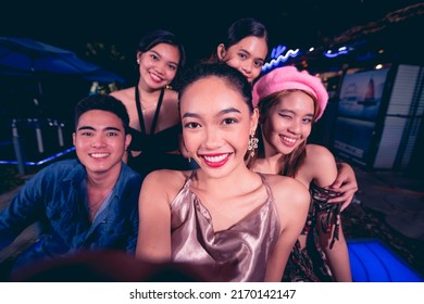 Five young friends take fun selfies while partying at a nightclub or bar. 5 people having a great time together. Nightlife scene. - Powered by Shutterstock