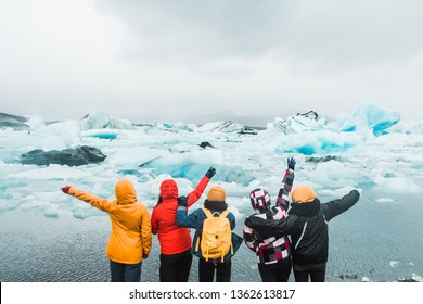 Five young girls standing on the sea shore covered in ice floes looking at the Nordic landscape in Iceland and enjoying life