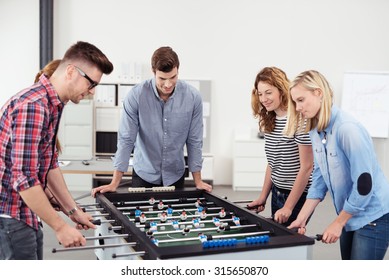 Five Young Office People Enjoying Table Soccer Game During Their Free Time At The Workplace.