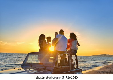 Five Young People Having Fun In Convertible Car At The Beach At Sunset.