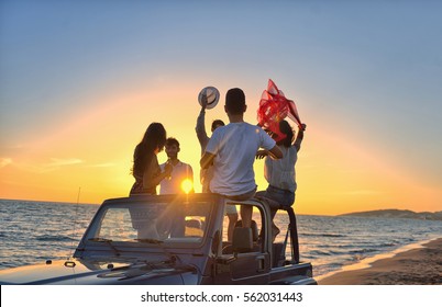 Five Young People Having Fun In Convertible Car At The Beach At Sunset.