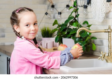 A five-year-old girl in a pink coat wants to help her parents wash apples in a vintage kitchen. Retro interior. Portrait of a child