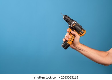 Fix it, fix a malfunction or tighten a bolt on a construction site. A man's hand holds a screwdriver or drill, a repair tool, a photo on a blue background.