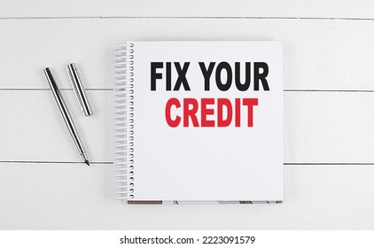 FIX YOUR CREDIT text written on a notebook on the wooden background - Shutterstock ID 2223091579
