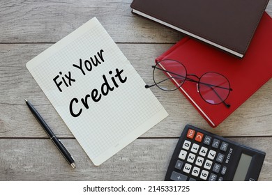 Fix Your Credit torn sheet of paper from a notebook with text on the desktop. next to the red notebook - Shutterstock ID 2145331725
