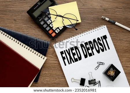 Fixed Deposit text on notepad with spring. wooden background