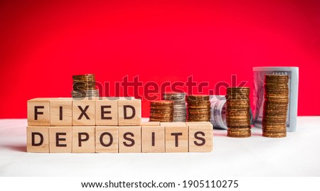 Fixed Deposit wording on selective focus with blurred gold coins and paper money in background