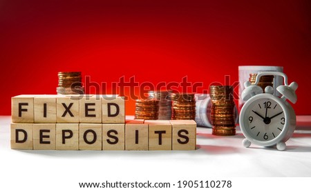 Fixed Deposit wording on selective focus with blurred gold coins, paper money and small clock in background
