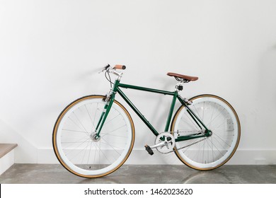 Fixed Green and Brown Bicycle in Modern Home, Fixie Bike inside hous​e, white wall background, isolated retro bicycle 