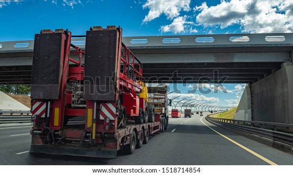 Fixed low loader trawl. Truck carries special\
equipment. Low loader trawl on the road. Car transportation on a\
truck. Low loader trawl rides on a freeway. Freight transport.\
Transportation of goods