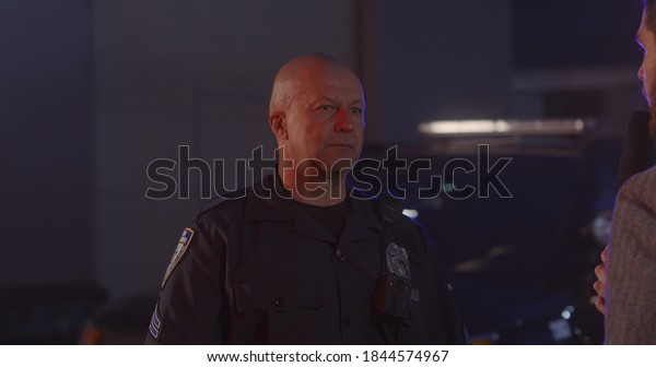 FIXED Reporter conducts interview with\
police representative on a crime scene. Police car lights flashing\
in the background. Model released for commercial\
use