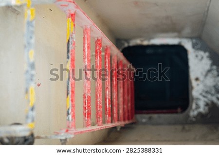 Fixed vertical access ladder installed inside a compartment on board an offshore support vessel, providing access to an upper or lower deck level through a confined passage. The ladder is painted red for high visibility, while the enclosed arrangement provides a dedicated access and escape route within the vessel's internal structure.