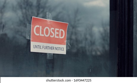 FIXED view of a sign saying Closed until further notice taped to a window. Coronavirus pandemic, small business shutdown