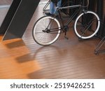 A fixie bicycle parked on a bicycle stand on the wooden floor