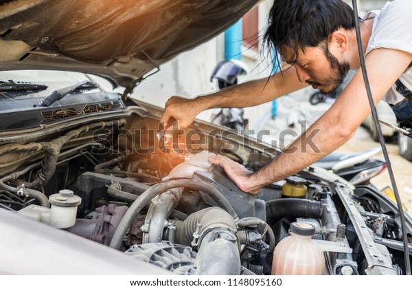 Fixing car engine in automobile repair garage.
Handsome mechanics in uniform are repairing car while working in
auto service